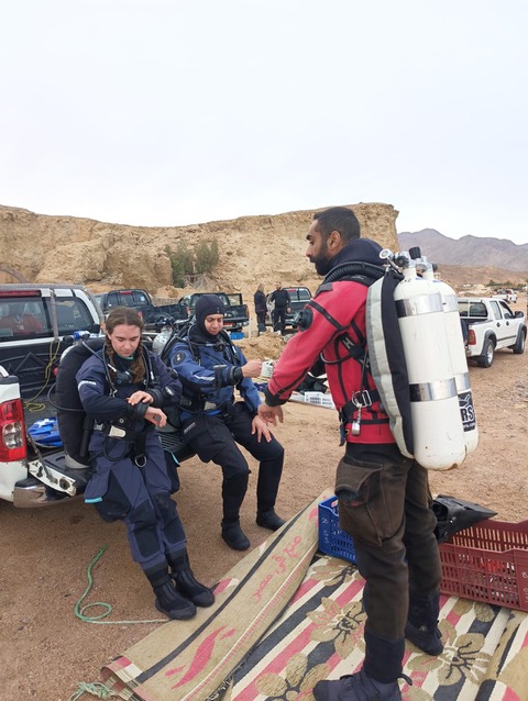 A diver helping a teammate kit up before a dive in the Sinai desert