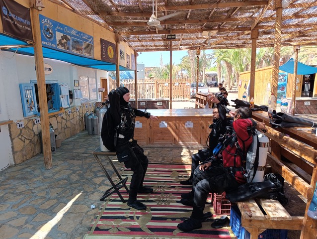 An instructor talking through a dive plan with a group of seated divers at Scuba Seekers