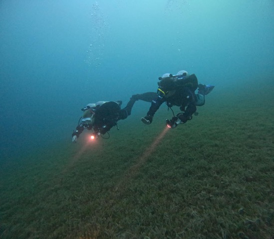 Two technical divers gliding side by side over the seagrass in the Red Sea