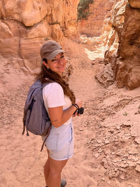 Aline exploring a desert canyon with her camera in hand