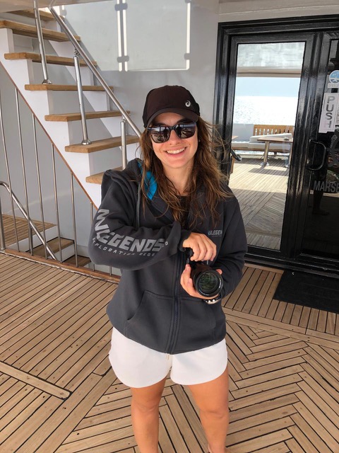 Aline on the deck of a Legends liveaboard holding her underwater camera